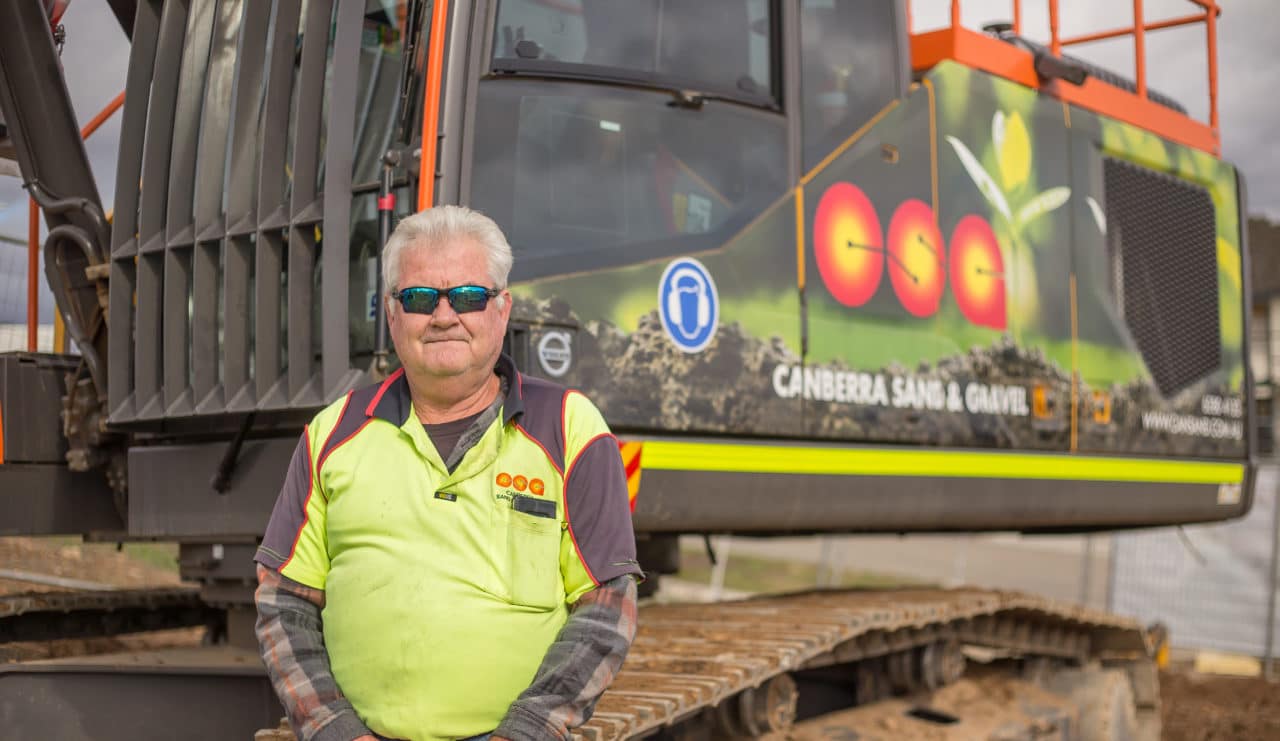 man standing next to a piece of heavy machinery